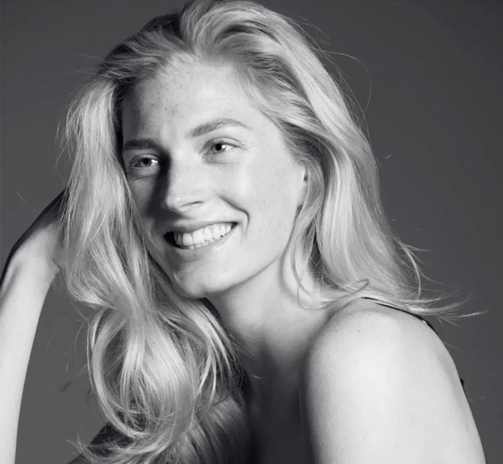 Portret van een lachende vrouw met lang, golvend haar.